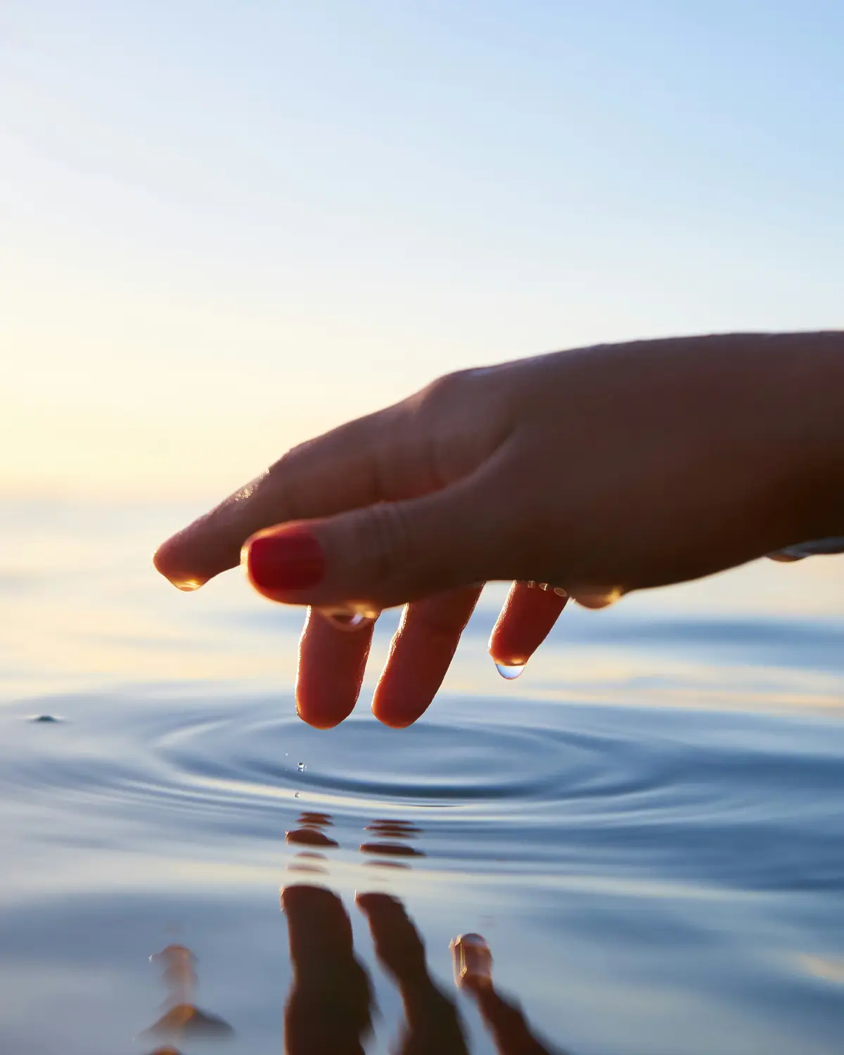Manos sobre agua en calma, en un gesto contemplativo bajo luz cálida